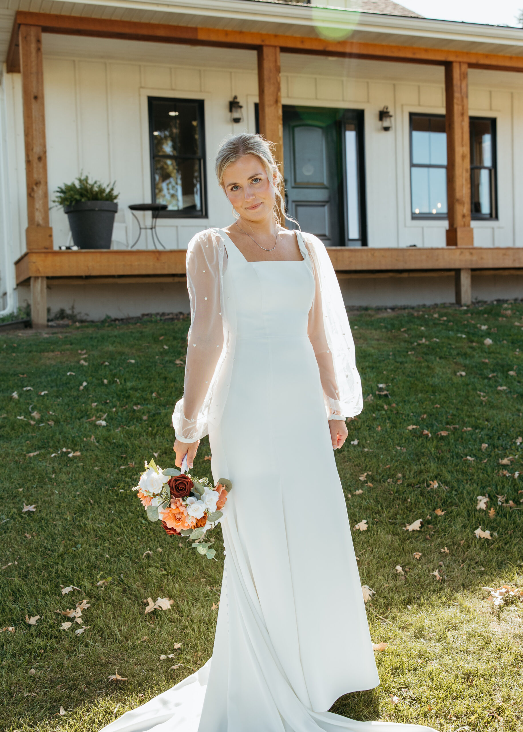 Professional Minneapolis wedding photography showing a beautiful bride in a sheer, long-sleeve pearl wedding dress at Genesis Ranch, styled by D'Amore Wedding and Event Planning.