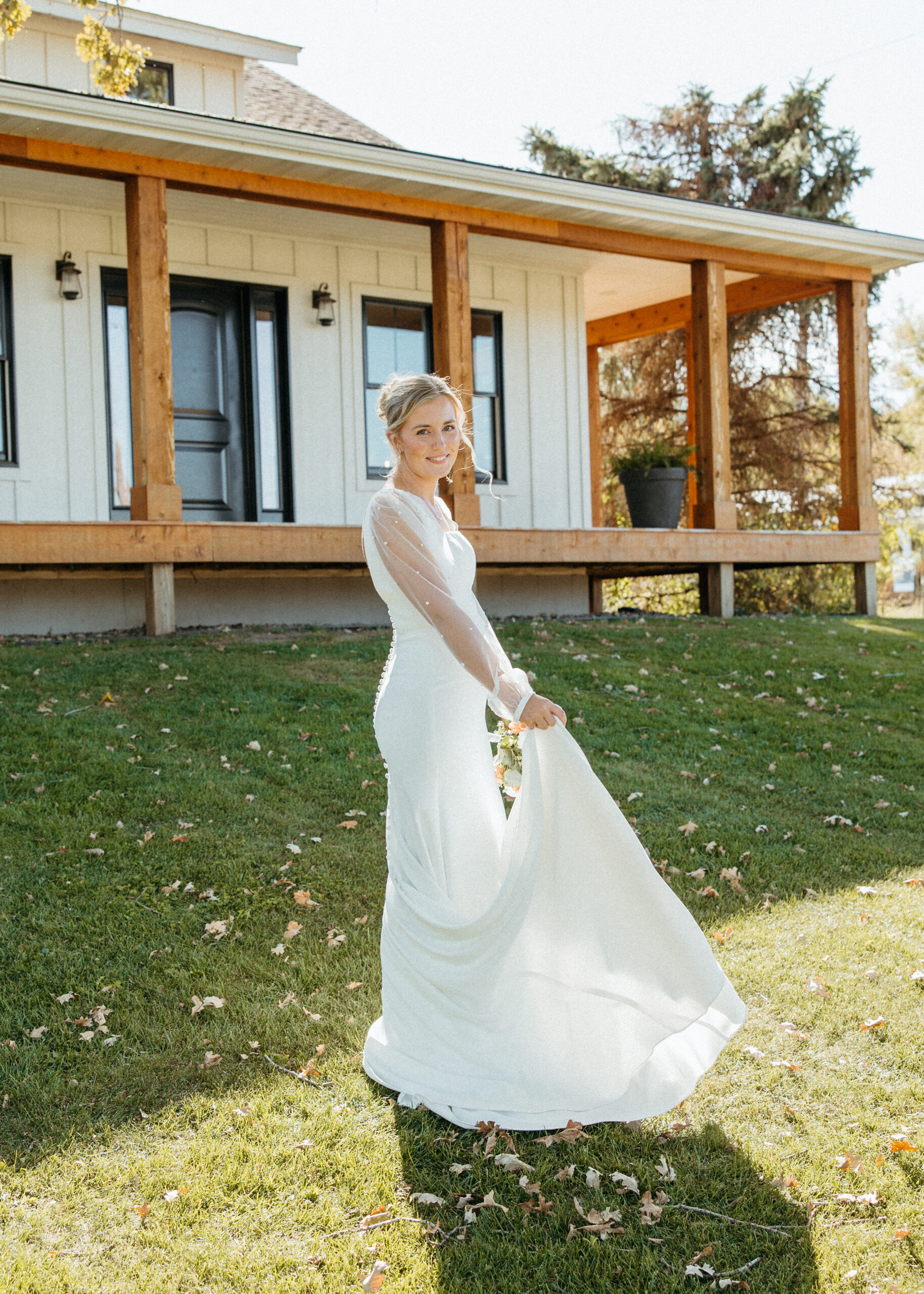 Professional Minneapolis wedding photography showing a beautiful bride in a sheer, long-sleeve pearl wedding dress at Genesis Ranch, styled by D'Amore Wedding and Event Planning.