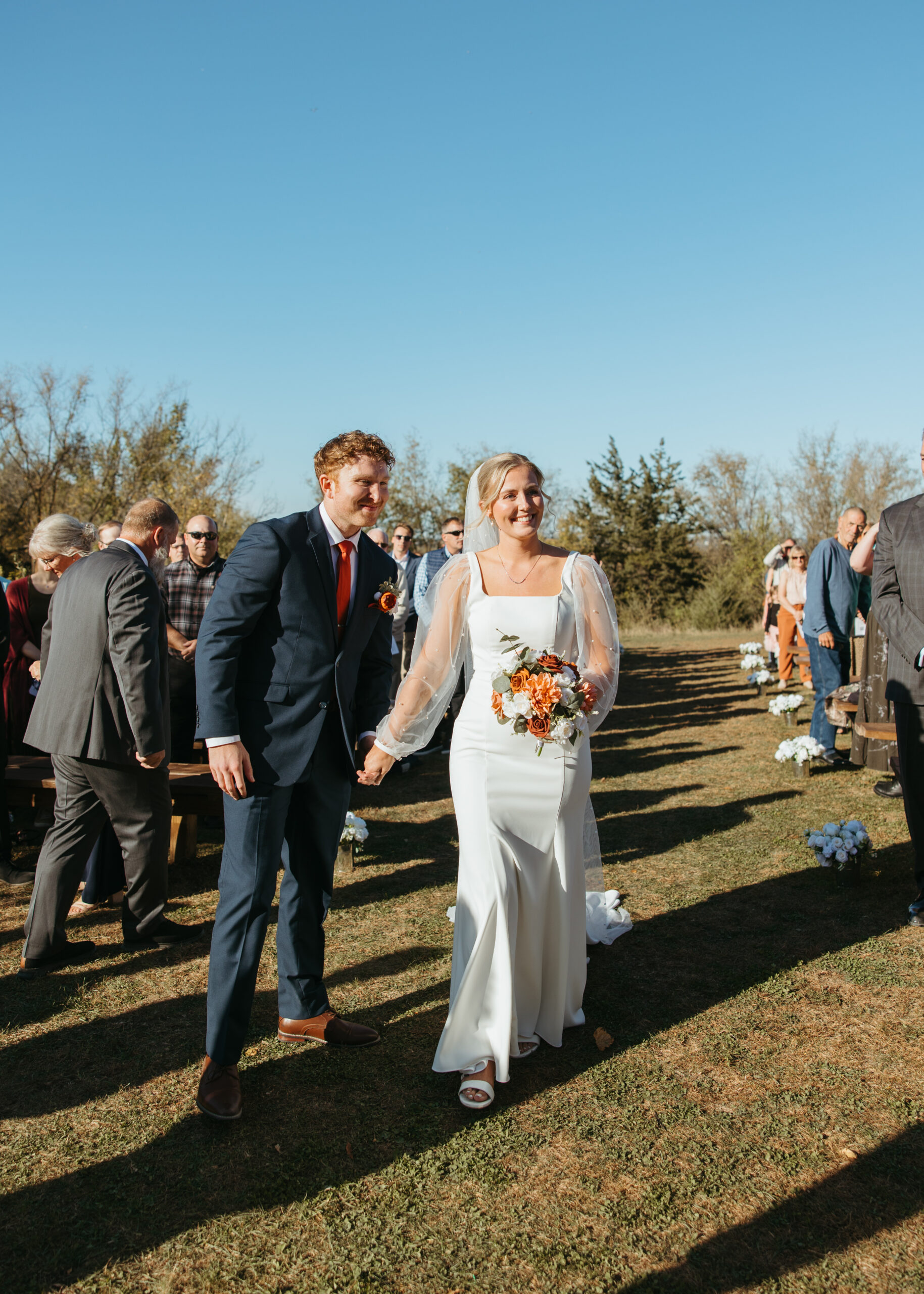 Emotional moment of a bride hugging her father at the end of the aisle during an outdoor Genesis Ranch ceremony, captured by a Minneapolis wedding photographer.