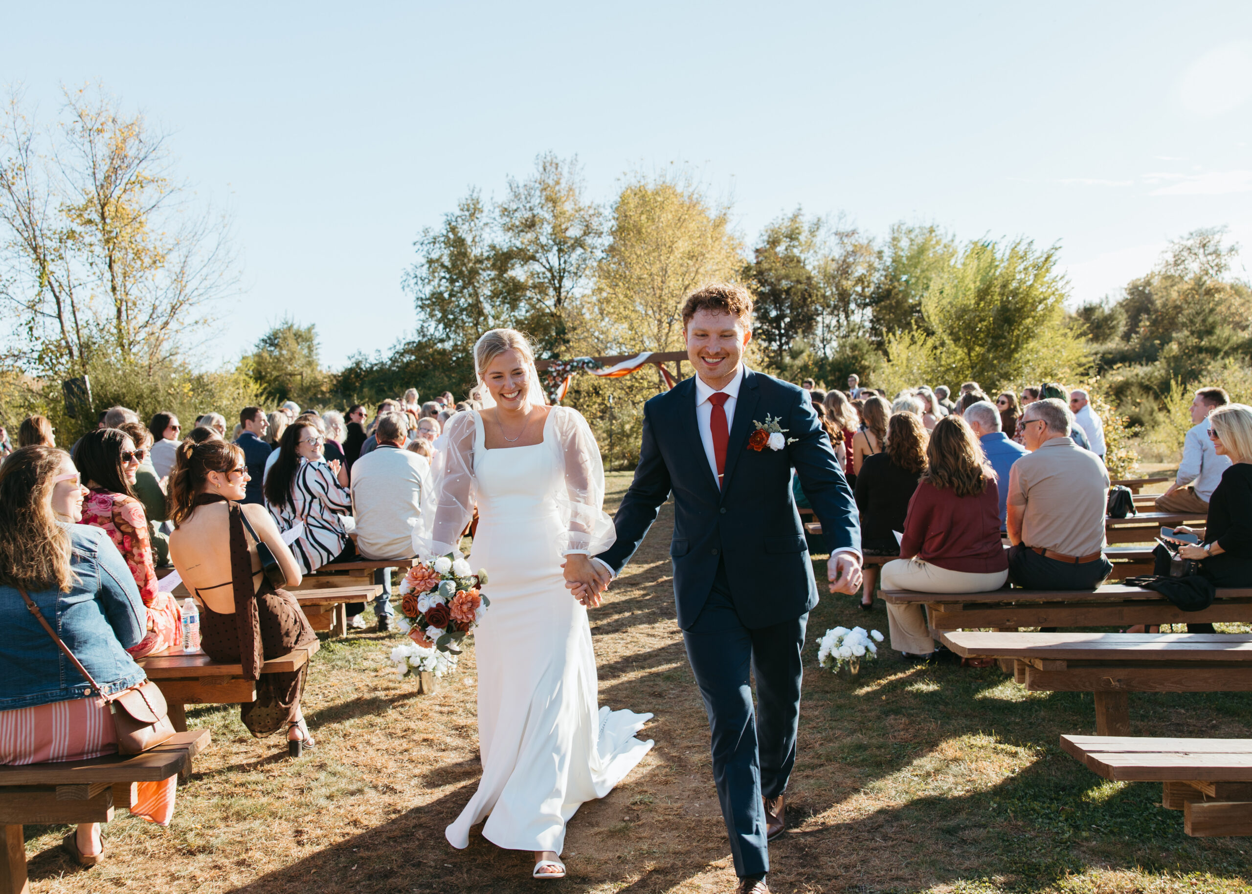 oyful bride and groom kissing and walking happily down the aisle as newlyweds at Genesis Ranch, captured by a Minneapolis wedding photographer.