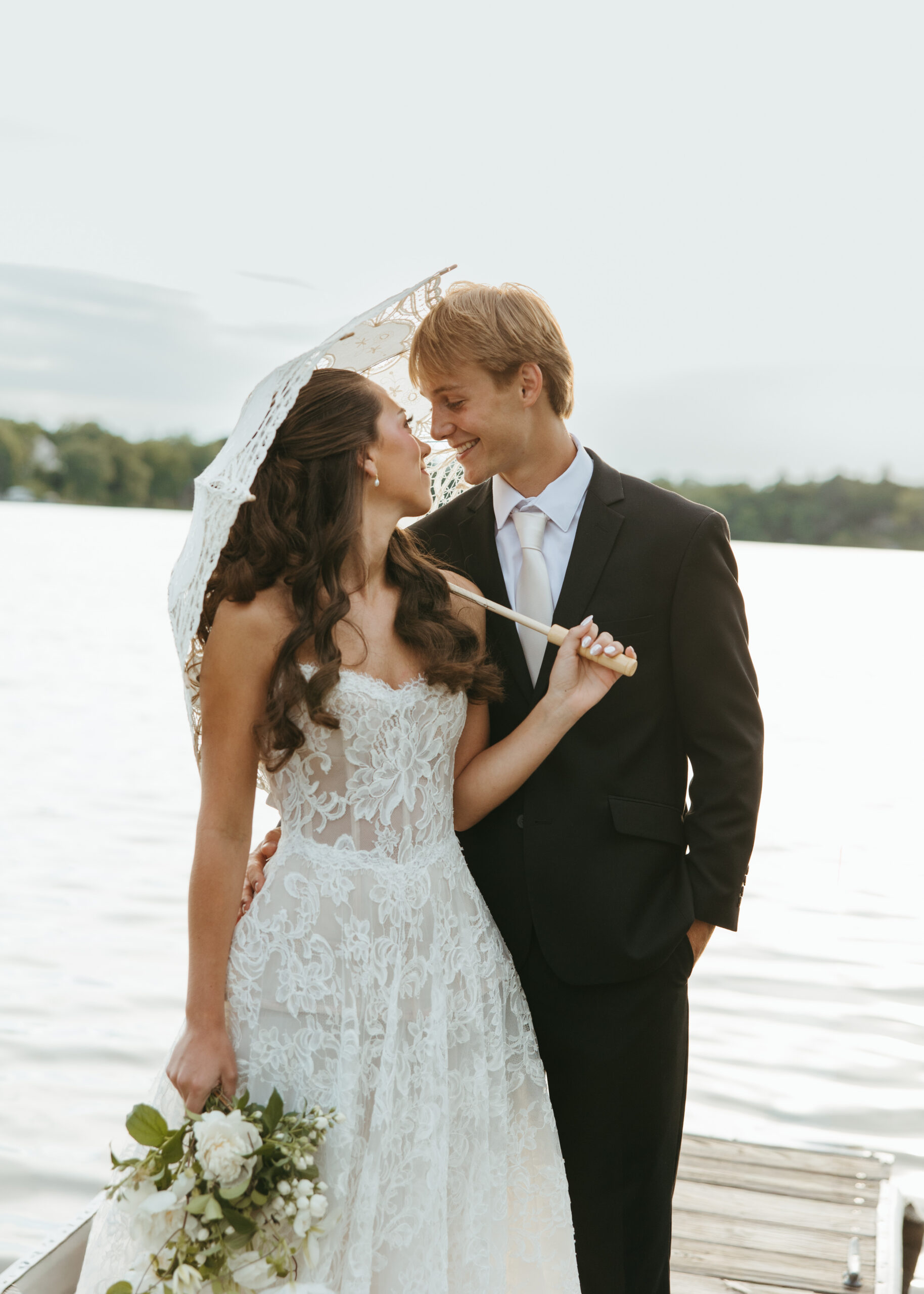 Bride in effortless attire from The Visionary Bride and groom standing along the shore at a Minneapolis lake.